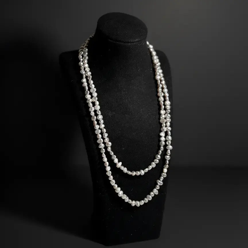 Baroque pearl eyewear chain displayed as a necklace on a jewelry stand, emphasizing organic shapes and refined details by Oculux Jewelry.
