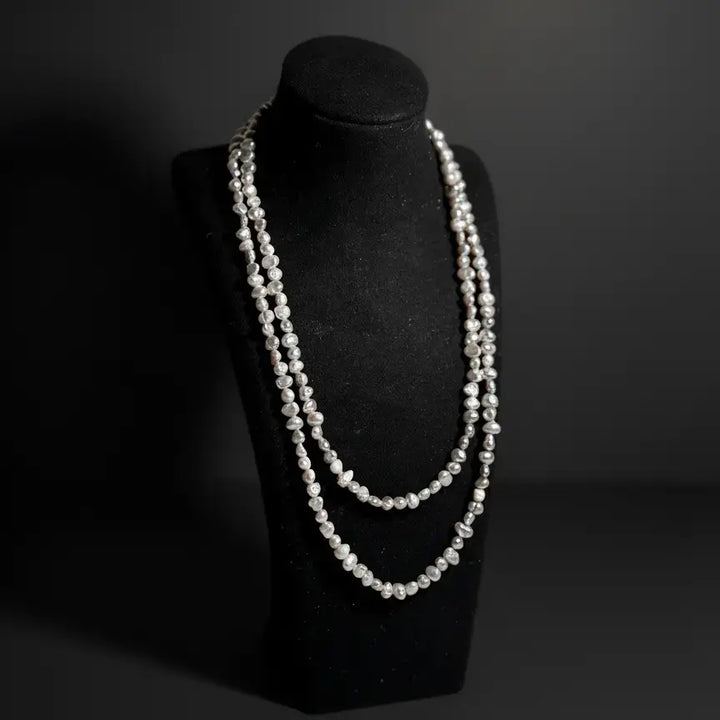 Baroque pearl eyewear chain displayed as a necklace on a jewelry stand, emphasizing organic shapes and refined details by Oculux Jewelry.