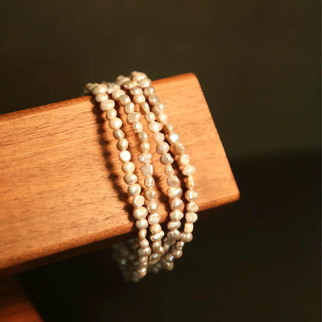 Baroque pearl wrap bracelet version of the eyewear chain displayed on wooden stand, elegant multi-functional gemstone jewelry by Oculux Jewelry.