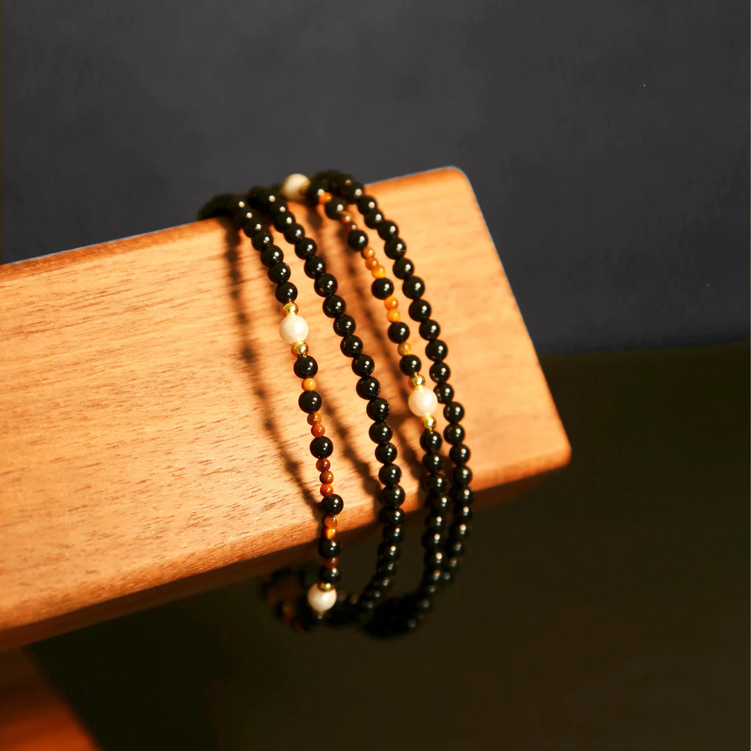 Black agate wrap bracelet version of the eyewear chain displayed on wooden stand, multi-functional gemstone jewelry.