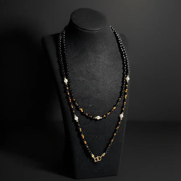 Black agate eyewear chain displayed as a necklace on a jewelry stand, handmade gemstone craftsmanship by Oculux Jewelry.
