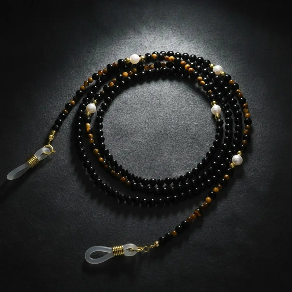 Black agate eyeglass chain displayed on velvet background, highlighting handmade faceted gemstone beads from Oculux Jewelry.